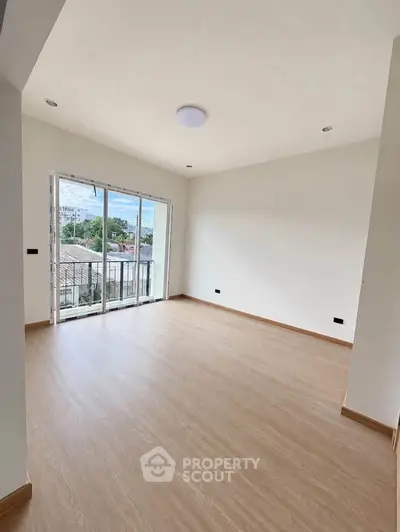 Spacious living room with wooden flooring and large windows offering natural light and scenic views.