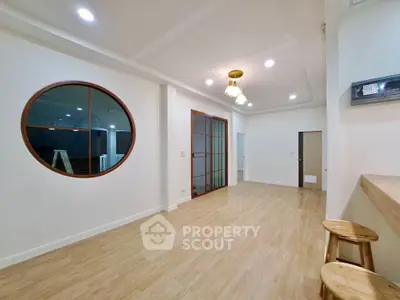 Spacious modern living room with unique round window and wooden flooring