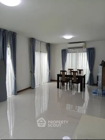Spacious dining area with elegant curtains and modern lighting in a bright, airy room.