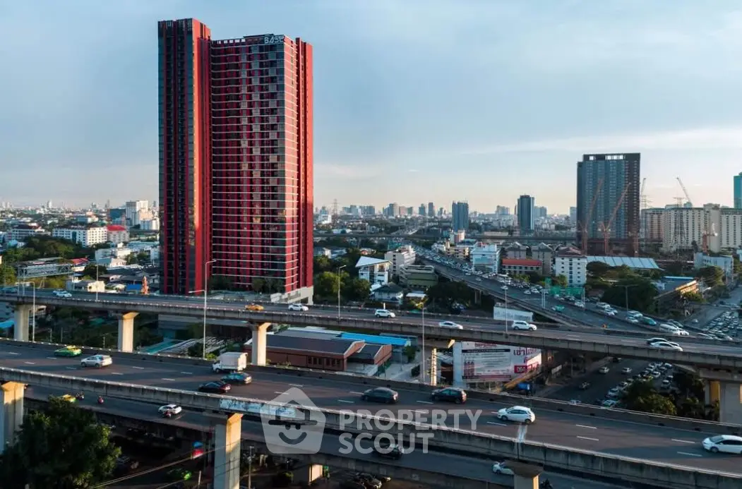Stunning cityscape view with modern red high-rise building and bustling highway.