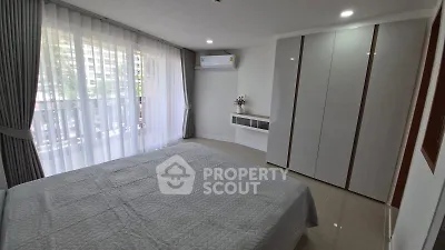 Spacious bedroom with large window and modern furnishings in a stylish apartment.