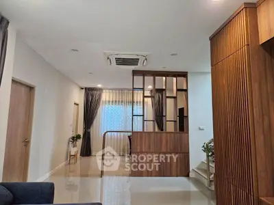 Modern living room with wooden accents and stylish partition, featuring sleek flooring and contemporary lighting.