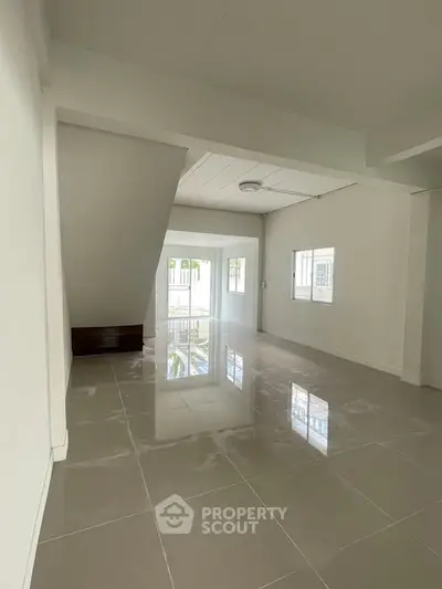 Spacious open-plan living area with glossy tiled floors and ample natural light.