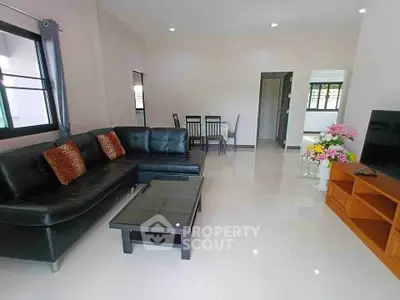 Spacious living room with modern black leather sofa and sleek glass coffee table