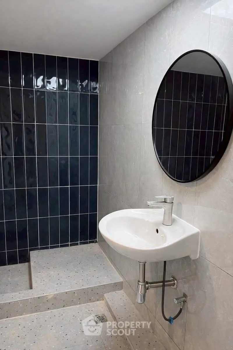 Modern bathroom with sleek round mirror and stylish blue tile accent wall.