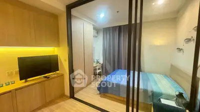 Modern bedroom with wooden flooring and glass partition, featuring cozy lighting and a stylish TV unit.