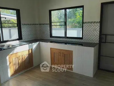 Modern kitchen with sleek countertops and large windows offering natural light