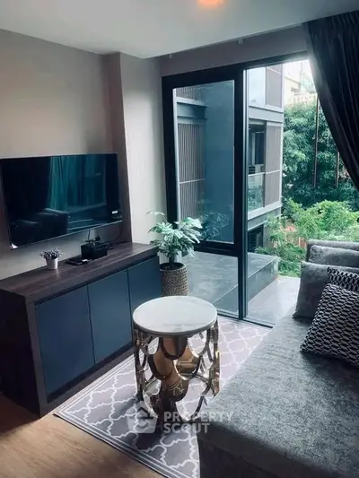 Stylish living room with modern decor and large window overlooking lush greenery.