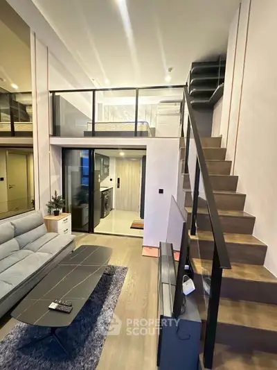 Modern loft apartment with stylish staircase and open living area, featuring sleek design and ample natural light.