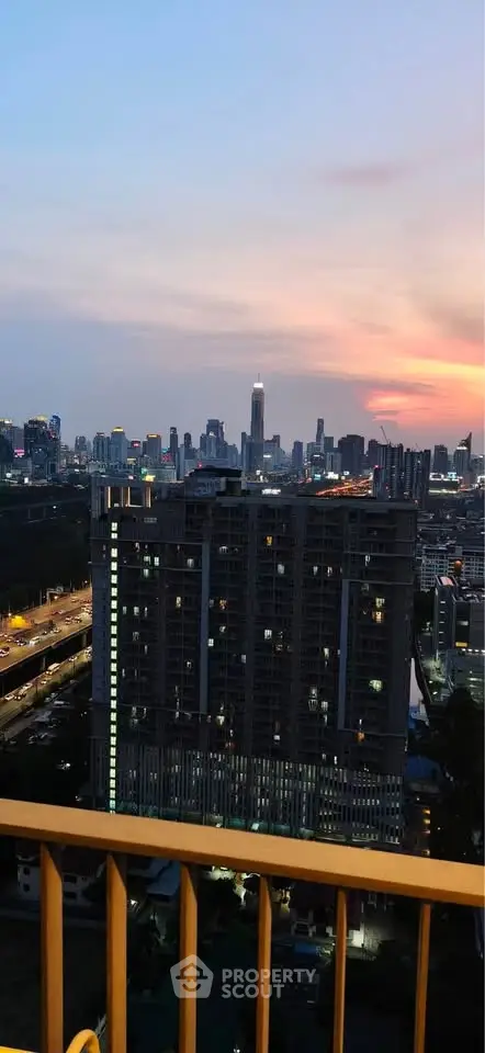 Stunning cityscape view from a high-rise balcony at sunset, showcasing urban skyline and vibrant city lights.