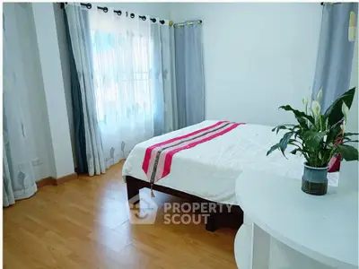 Bright and airy bedroom with wooden flooring and stylish decor
