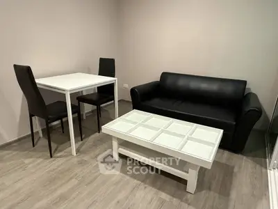Modern minimalist living room with sleek black sofa and dining set