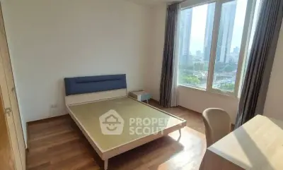 Bright bedroom with large windows and city view, featuring a modern bed and wooden flooring.