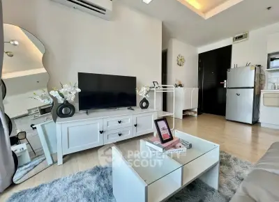 Modern living room with stylish decor, TV unit, and cozy rug in a bright apartment.