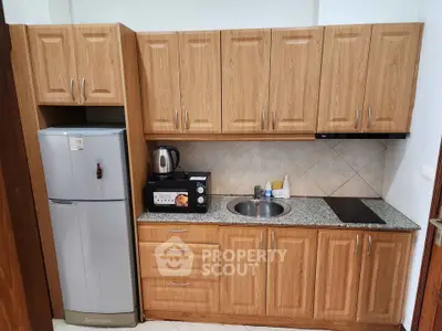 Compact kitchen with wooden cabinets, granite countertop, and modern appliances.