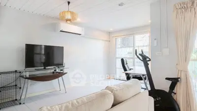 Modern living room with TV, exercise bike, and natural light
