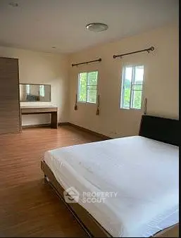 Spacious bedroom with large windows and wooden flooring