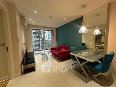 Modern living room with vibrant red sofa and stylish dining area, featuring a balcony view.