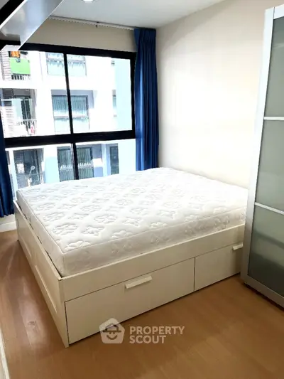 Modern bedroom with large window and storage bed in urban apartment
