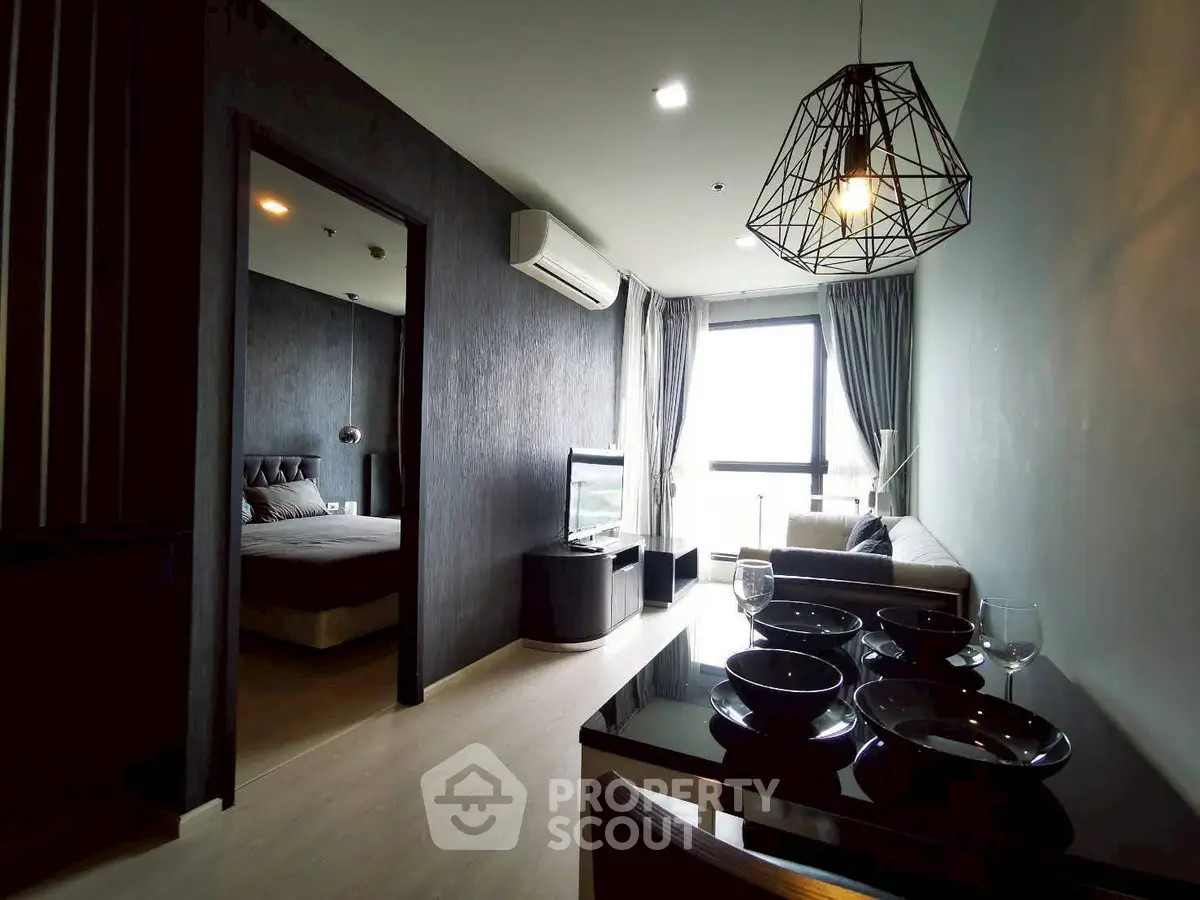 Modern apartment interior with open living room and dining area, featuring stylish lighting and large windows.