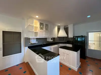 Spacious kitchen with modern black countertops and white cabinetry, featuring an open layout and sleek appliances.