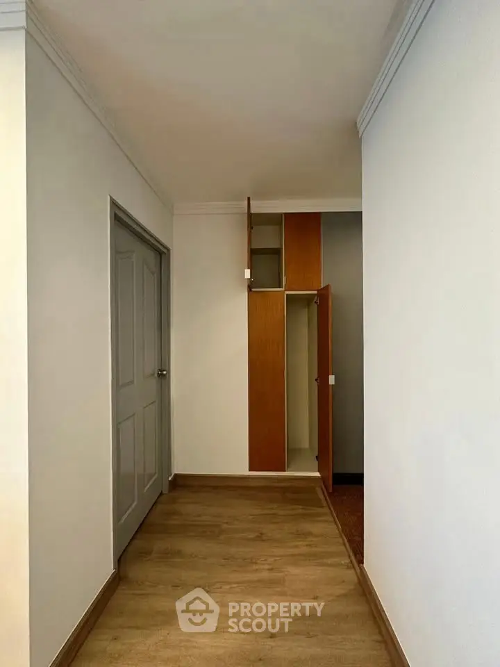 Spacious hallway with wooden flooring and built-in storage in modern apartment.