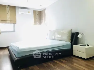 Modern bedroom with sleek design and natural light, featuring a stylish bed and wooden flooring.