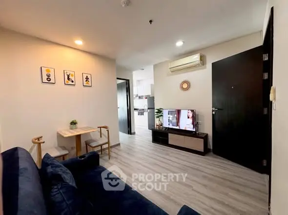 Modern living room with stylish decor and open layout, featuring a cozy seating area and wall-mounted TV.