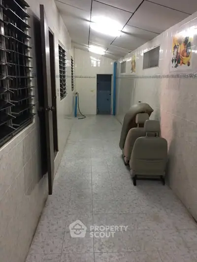 Narrow tiled corridor with car seats and wall art, potential storage space