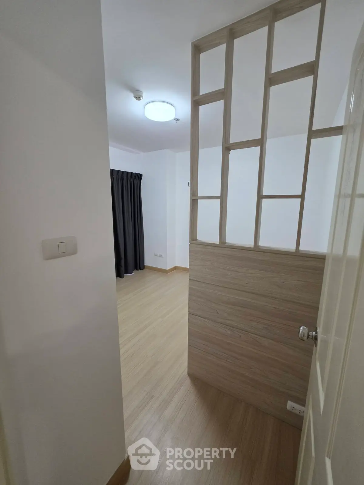 Modern minimalist room with wooden flooring and partition, ideal for cozy living space.