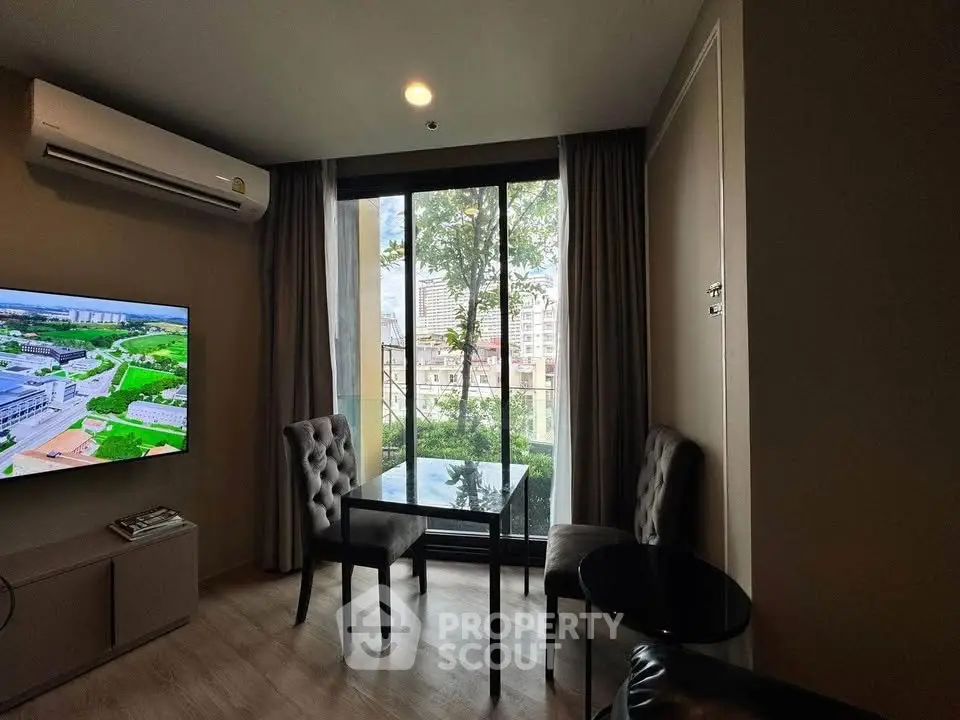 Modern living room with large window and city view, featuring elegant chairs and air conditioning.