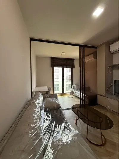 Modern living room with large window, sleek furniture, and natural light in a stylish apartment.