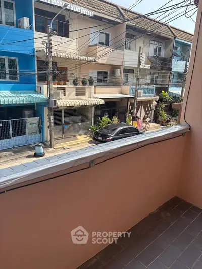 Charming balcony view of a vibrant street with colorful buildings and parked cars.