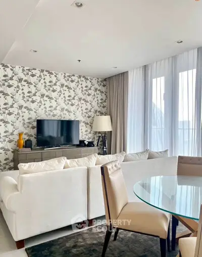 Stylish living room with modern decor, featuring a cozy white sofa, flat-screen TV, and elegant wallpaper.