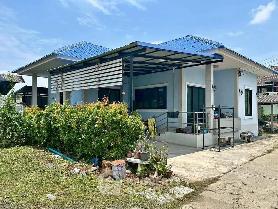 Charming single-story home with blue roof and lush garden in serene neighborhood.