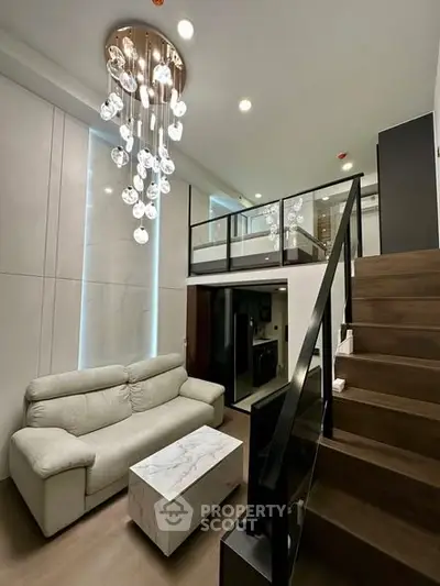 Modern loft-style living room with elegant chandelier and mezzanine level