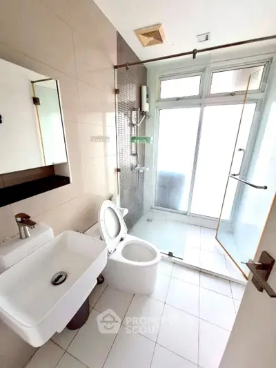 Modern bathroom with glass shower and sleek fixtures in bright apartment.