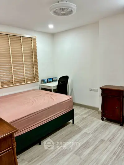 Cozy bedroom with wooden furniture and natural light, perfect for relaxation and comfort.