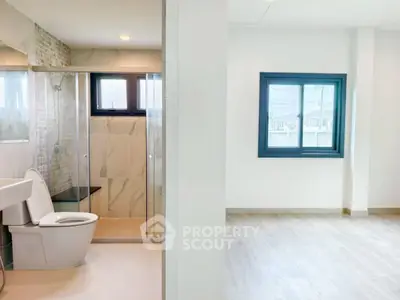 Modern bathroom with glass shower and adjacent bright room