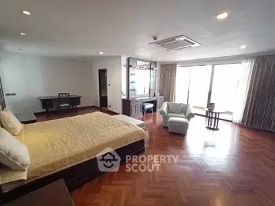 Spacious bedroom with elegant wooden flooring and large windows for natural light.