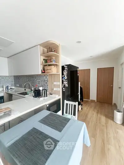 Modern kitchen with sleek cabinetry and open layout, featuring a stylish backsplash and wooden flooring.