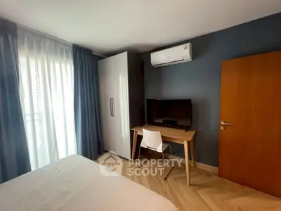 Modern bedroom with sleek furniture and air conditioning, featuring a cozy workspace and ample natural light.