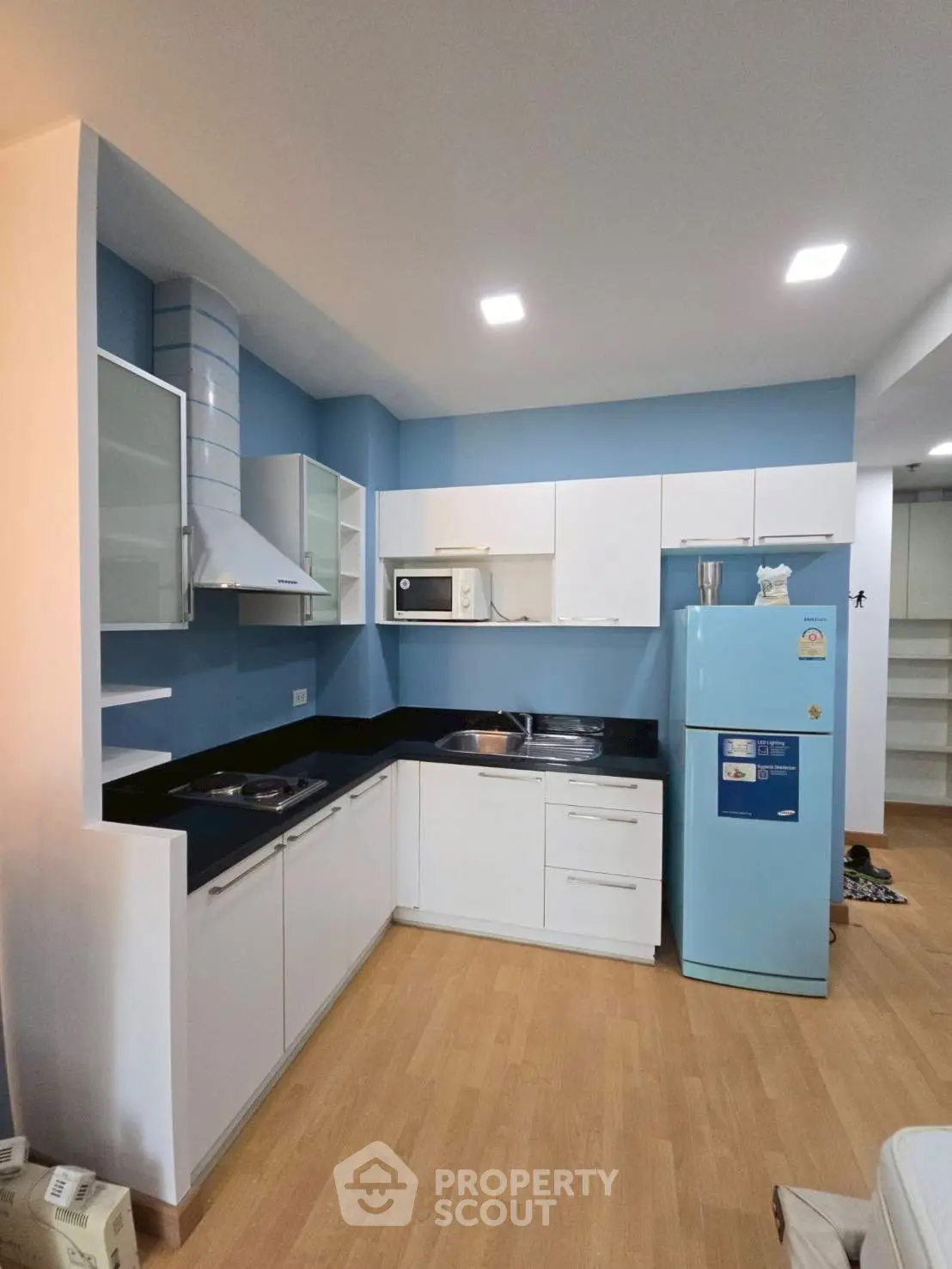 Modern kitchen with blue accents, sleek cabinetry, and appliances in a stylish apartment.