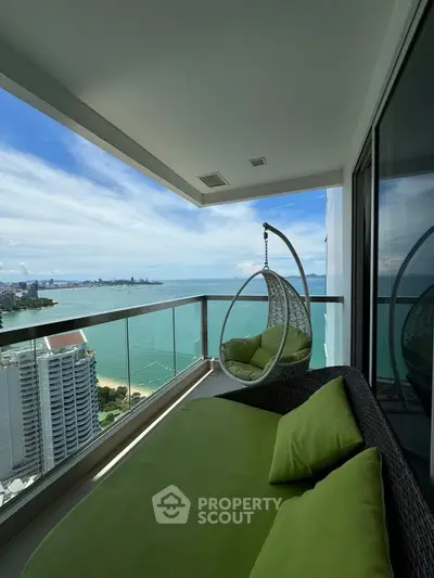 Luxurious high-rise balcony with stunning ocean view and cozy seating area.