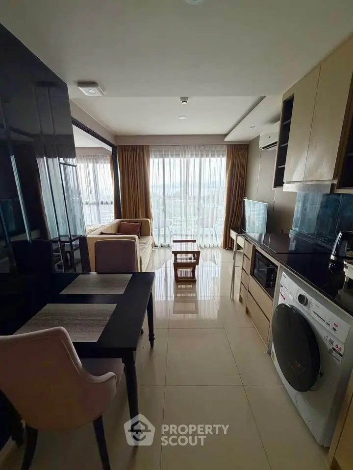 Modern open-layout living room with kitchen, featuring sleek furniture and large windows with a stunning view.