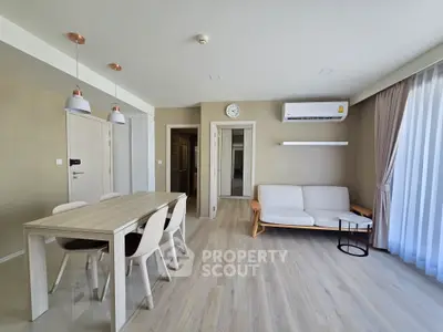 Modern living room with dining area and air conditioning, featuring sleek furniture and natural light.
