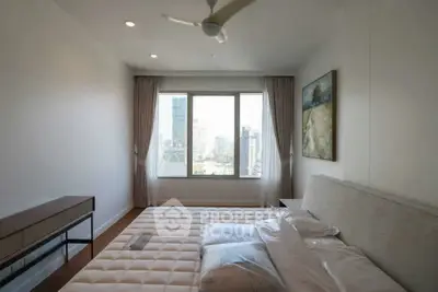 Modern bedroom with city view, featuring a large window and elegant decor.
