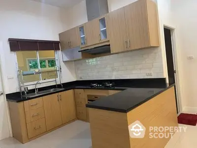 Modern kitchen with sleek wooden cabinets, black countertops, and a gas stove, featuring a bright and airy design.