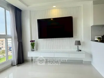 Modern living room with large TV and elegant decor in bright apartment.