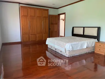Spacious bedroom with wooden flooring and large wardrobe in a modern home.
